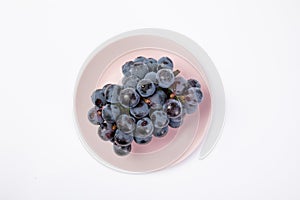 Top view of a bunch of fresh grapes with water drops on the plate isolated on white background