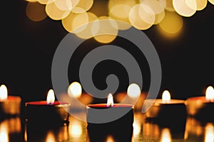 Top view of burning candles with festive bokeh on a black background. Holiday concept. The concept of prayer and hope