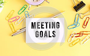 Top view of a business card with text MEETING GOALS, on a yellow background.