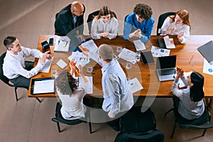 Top view of business conference, meeting. Young colleagues, co-workers, students during work process at office, indoors