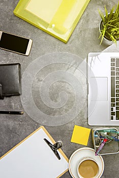 Top view of business desk with laptop, coffee, potted plant, document file, mobile phone and business accessories