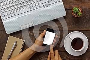 Top view business man using mobile phone and coffee, laptop,notebook,cactus on wooden office desk.