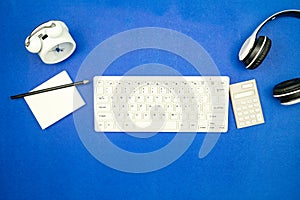 Top view of business objects Keyboard,mouse,Headphone,paperwork with pencil and alarm clock on blue paper background Minimal flat
