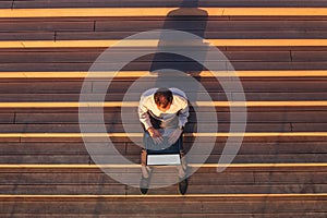 Top view of business professional using blank screen laptop and sitting on outdoor steps