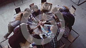 Top view of business team working at office. Young mixed race group of people puts palm together on centre. Slow mo