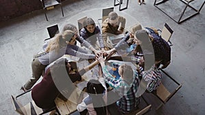 Top view of business team working at trendy loft office. Young mixed race group of people puts palm together on centre.