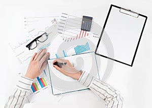 Top view of business womans hands makes a financial report on white table