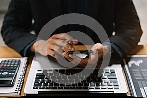 Top view of a businessman hand using a mobile phone and a laptop to settle a laptop online shopping omni channel is at the desk in