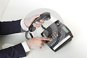 Top view of businessman hands dialing out on a black deskphone