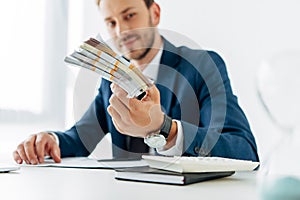 View of businessman holding envelope with bribe near laptop
