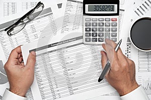 Top view of businessman working with financial statements. Modern black office desk with notebook, pencil and a lot of things.