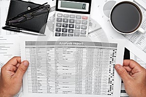 Top view of businessman working with financial statements. Modern black office desk with notebook, pencil and a lot of things.