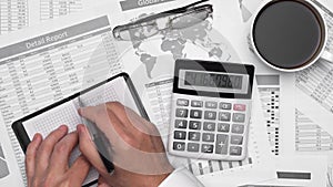 Top view of businessman working with financial statements. Modern black office desk with notebook, pencil and a lot of things.