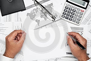 Top view of businessman working with financial statements. Modern black office desk with notebook, pencil and a lot of things.