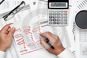 Top view of businessman working with financial statements. Modern black office desk with notebook, pencil and a lot of things.