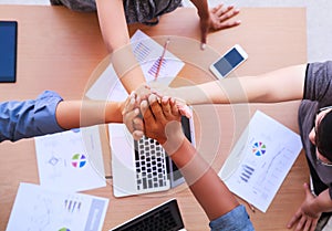 Top view of businessmen and businesswoman standing and stacking hands over table in a meeting with copy space at mobile office.