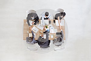 Top view of businessmen shaking hands sitting at conference table during team meeting,