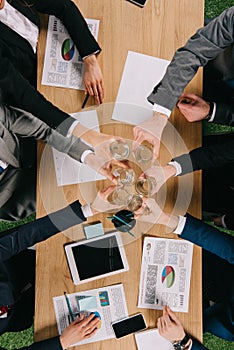 Top view of businesspeople clang glasses together at table