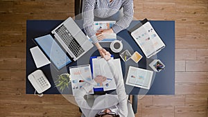 Top view of businesswomen shaking hands before analyzing management statistics paperwork