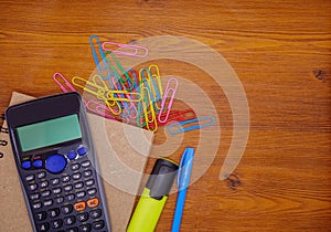 Top view calculator on notebook and stationery on brown wooden background