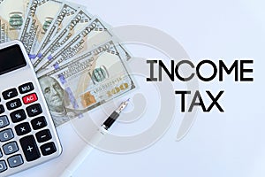 Top view of calculator,pen and dollar bank note on white background written with Income Tax.