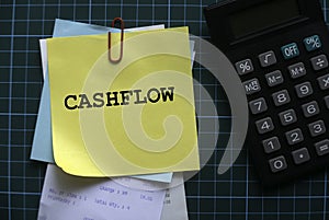 Top view of a calculator and a stack of memo notes written with Cashflow on a green square background