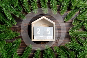 Top view of calendar decorated with a frame made of fir tree on wooden background. The twenty fifth of December. Christmas time