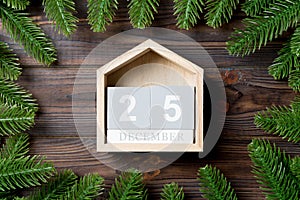 Top view of calendar decorated with a frame made of fir tree on wooden background. The twenty fifth of December. Christmas time