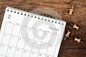 Top view Calendar desk 2022 on February month, The concept of planning and deadline with push pin on wooden table background