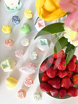 top view of candle figures, a plate of strawberries and a bouquet of flowers