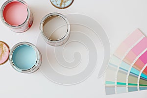 Top view of cans with paint and color palette on white background.