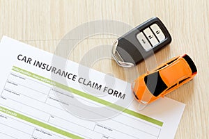 Top view of car insurance claim form with car key and car toy on