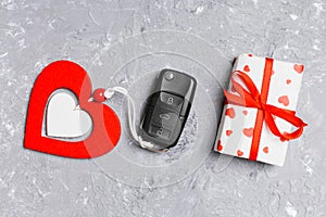 Top view of car key, gift box and heart as a present for Valentine`s day on cement background. Romance concept