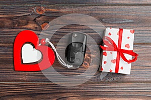 Top view of car key, gift box and heart as a present for Valentine`s day on wooden background. Romance concept