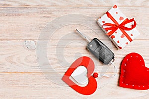 Top view of car key, gift box and heart as a present for Valentine`s day on wooden background. Romance concept with copy space