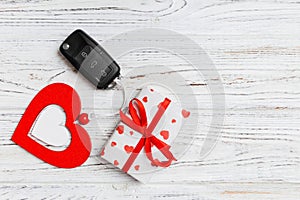 Top view of car key, gift box and heart as a present for Valentine`s day on wooden background. Romance concept with copy space