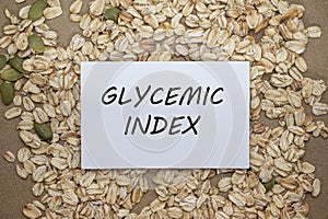 Top view of card with text Glycemic index on oat and seeds background. Healthy eating concept