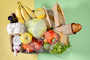 Top view of cardboard box with fresh food products on green-yellow background. Safe delivery. Top view