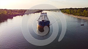 Top view of cargo ship sailing on Volga. Footage. Long boat for cargo transportation on river on background of beach