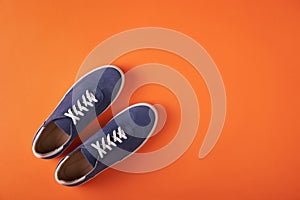 Top view of casual blue suede sneakers on orange background