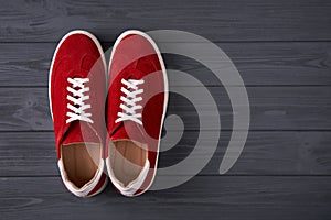 Top view of casual red suede trainers on grey wooden planks