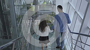 Top view of caucasian family walking down the modern stairs in the airport. Father and daughter going to the departure