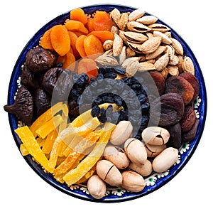 Top view of Central Asian dried fruits and nuts in a typical blue ceramic plate isolated on white background. Dried