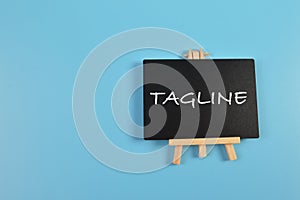 Top view of chalkboard written with TAGLINE isolated on blue background