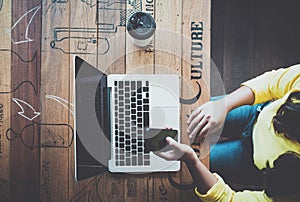 Top view of charming young hipster girl hands using on her smart phone sitting at wooden table in a coffee shop