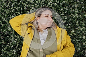 Top view of a charming young woman has closed her eyes and is lying on a blooming meadow