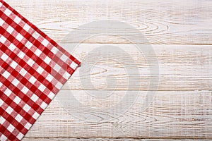 Top view of checkered tablecloth on white wooden table.