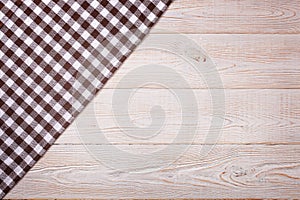 Top view of checkered tablecloth on white wooden table.
