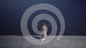 Top view of cheerful Caucasian young woman spinning on river bank. Wide shot of happy chubby girl enjoying sunny day