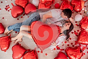 Top view of cheerful young couple lying on floor near red white balloon heart shaped, Valentines Day